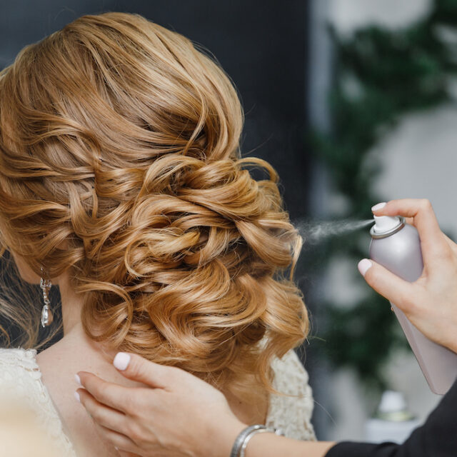 Master stylist makes the bride wedding hairstyle using spray lacquer fixing